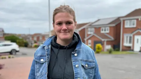 BBC Portrait of Bethany Emsen standing in front of houses