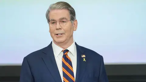 Bloomberg através da Blue Tie com Blue Tie com listras diagonais vermelhas e amarelas durante a Conferência do Federal Reserve Board Community Bank em Washington DC.