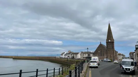 A view of a church by the sea and a road.