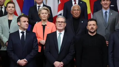 Getty Images Emmanuel Macron, France's president, bottom left, Keir Starmer, UK's prime minister, bottom center, and Volodymyr Zelenskiy, Ukraine's president, and other world leaders pose for a group photo at a summit in London.