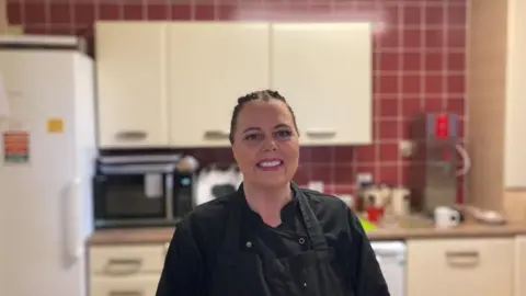 Annie Cleaver in a black top and black apron