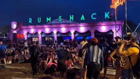 The Rum Shack - a building lit up with purple and pink lighting with the words Rum Shack in green on the roof.