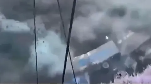 A lorry being swept away on its side