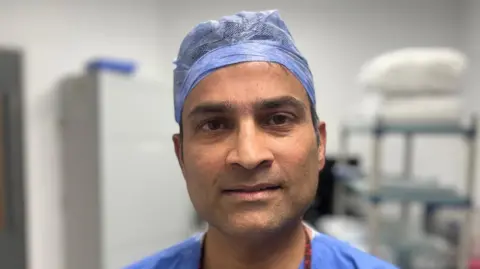 Surgeon in blue scrubs looking directly at the camera