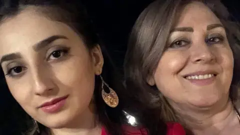 Roya Pirae Two women close together. A young, dark haired woman on the left and an older, brown haired woman on the right.