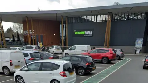 A Google street view image showing the front of a motorway service station building