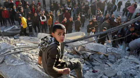 A Palestinian child sits at the site of an Israeli strike, during Israel's conflict with Hamas, in the Nuseirat refugee camp in the central Gaza Strip, on December 13, 2024.