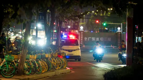 BBC/ ED LAWRENCE A police van and motorcylists waiting on the street outside the stadium venue on 12/11/24. It is night time.