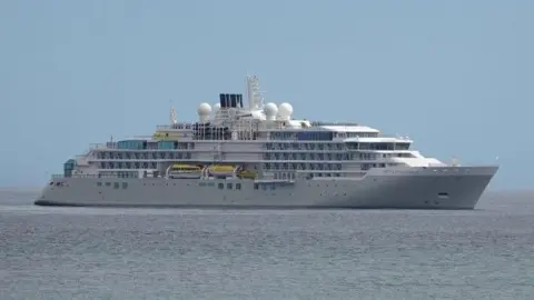 A large cruise ship sits on a still sea.