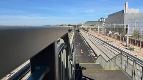Tom Jackson/BBC A staircase leads down to a train station platform which has railway lines either side. There are cones on the platform and next to the railway lines on the right.