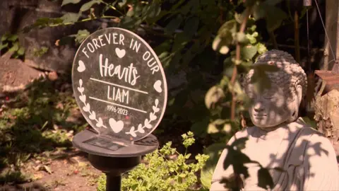 A placard in the garden reads 'Forever in our Hearts, Liam, 1996-2023