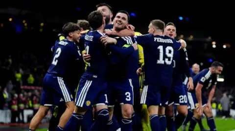 Scotland footballers in navy jerseys celebrate following a goal 