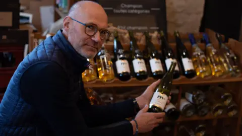 BBC Frédéric Brochet met een fles alcoholvrije wijn in de hand