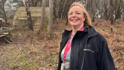 Tracey Churcher smiling for the camera at the Purbeck Nature Reserve. It is an overcast day.