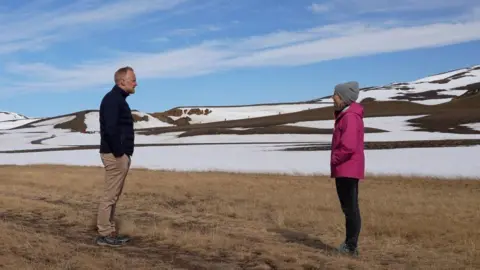 Bjorn Por Guðmundsson talks to Adrienne Murray with the rim of Krafla Volcano in the distance