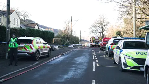 A police cordon has been put across a residential road, with emergency services vehicles parked at the scene