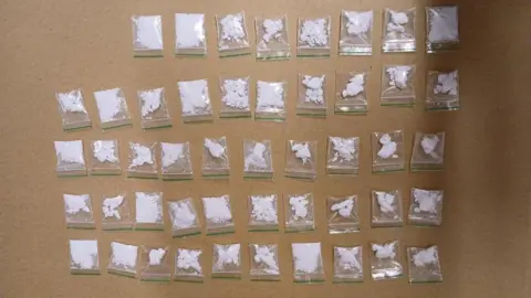 Devon and Cornwall Police 48 small bags of white power are seen laid out on a table 