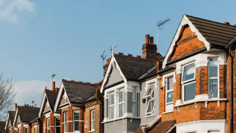 Getty Images A row of brick houses with triangular roofs on a sunny day.