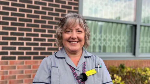 A woman who works for the NHS standing outside St. Oswald's Hospital in Ashbourne, Derbyshire.