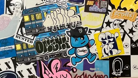 Stickers including a small blue creature, a train and a sign which says 'busted'