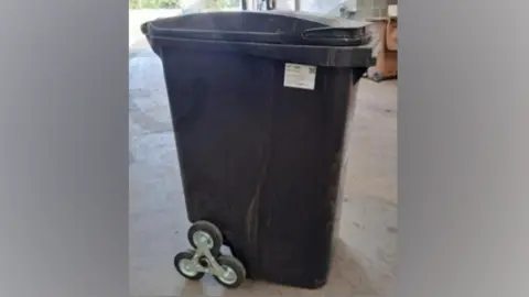 Stevenage Borough Council A black wheelie bin which has been modified with three wheels on each side.