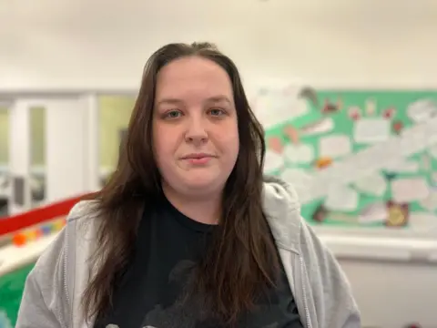 Student Amy Shaw, smiling, with long brown hair and wearing a black top and grey hoodie