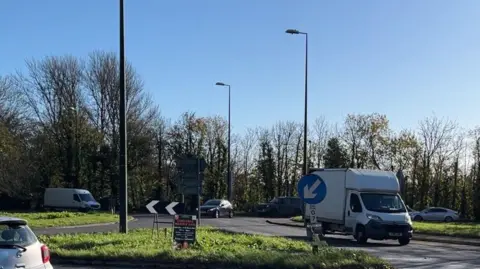 George Carden / BBC The Ford Roundabout with vehicles going around it. The roundabout connects the A27 and A284 and has five exits