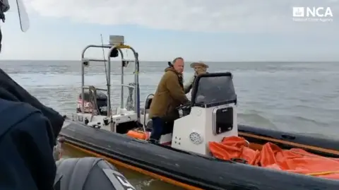 National Crime Agency A screenshot from bodycam footage showing the two defendants on an inflatable boat in the sea