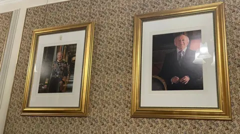 Two portraits hang side by side. One is of King Charles II and the other is of Irish President Michael D Higgins