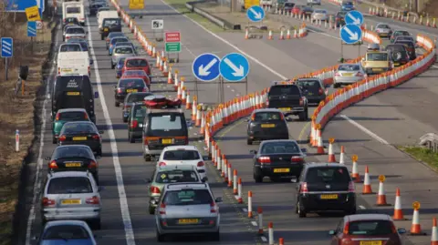 PA Media A traffic jam on a busy dual motorway, with traffic cones and lots of arrow signs.