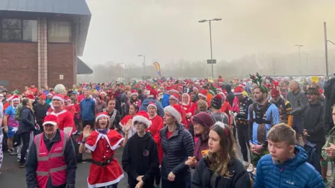 Crowds of runners, many in Santa hats, gather outside