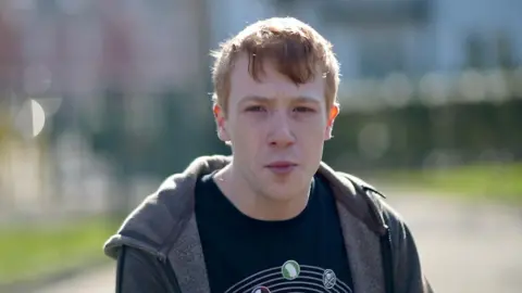 Jamie Niblock/BBC Connor Hickman wearing a T-shirt and jumper 