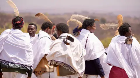 The youth of Anesisa IFA / BBC wear ostrich wings on their heads.