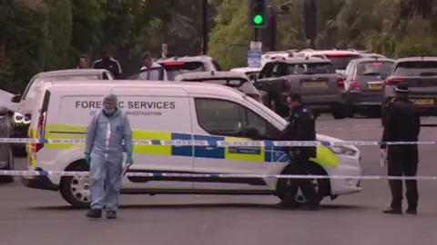 A forensic van and police officers on Kingsbury Road behind police tape