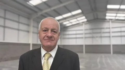 LDRS A man in a suit stood inside a large warehouse