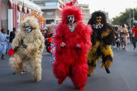 CEM OZDEL / GETTY IMAGES People marching down a road wearing voluminous costumes of different colours.