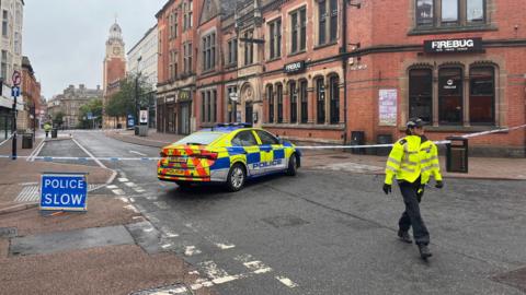 A police cordon and police car, positioned in Market Street in Leicester, where the stabbing took place