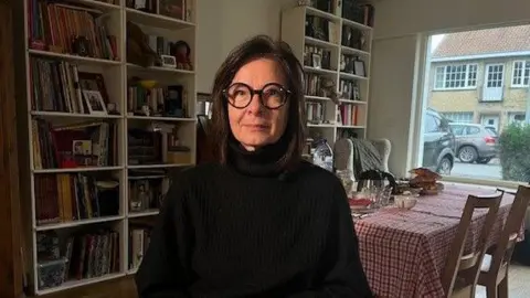 Jack Valpy/BBC Ann sitting in the living room of her home near Bruges