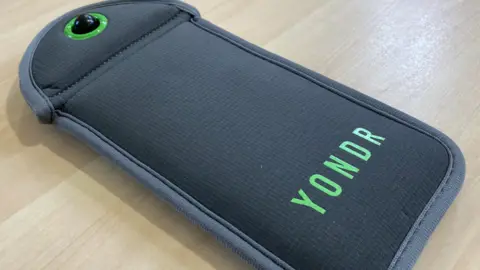 The picture shows the magnetic pouch on a table.  The pouch is grey in colour with YONDR written in green.