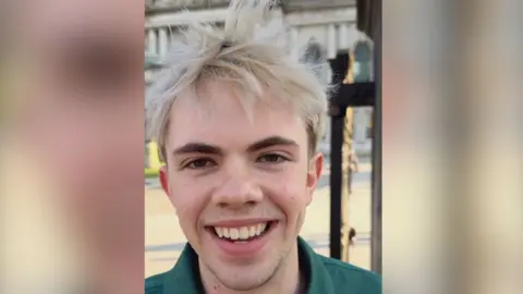 A man with blonde hair is smiling into the camera. 