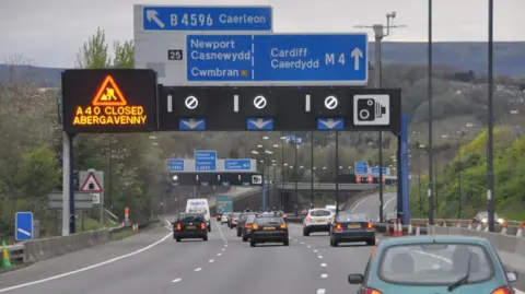 A motorway in Newport with blue signs indicating that drivers should be in the left hand lane for Newport and Cwmbran, and the right two lanes for Cardiff.