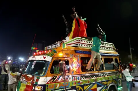 Reuters Fans lean out of the windows of a minibus taxi in celebration.