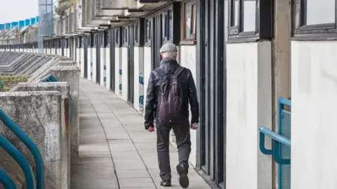 An unidentified man walking on the crescent walkway of Alexandra Road estate in London, UK