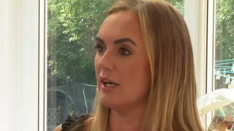 Danielle Horan speaking in a TV interview sat in front of a window looking out onto her garden at her home