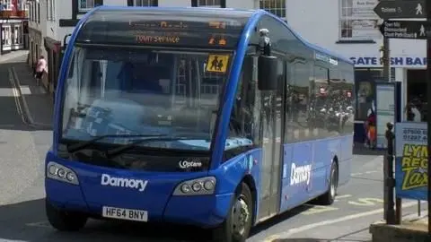 A blue single-decker bus, number 71, at a bus stop in Lyme Regis town centre