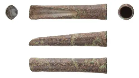 Andrew Williams/Norfolk County Council Five views of a bronze woodworking gouge against a white background. From the top there are three views. On left the cutting edge from above; middle the shaft from above showing the cast gouge running from its cutting edge on the left up towards its middle; the shaft from above showing its socket cavity. In the middle the tool from the side tapering towards the cutting edge on the left to the socket on the right. The bottom view shows the tool from behind with its cutting edge on the left and its socket on the right. 