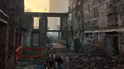 Nooko The inside of a the burnt former Royal Clarence Hotel in Exeter. There are gates and red barriers to the left.