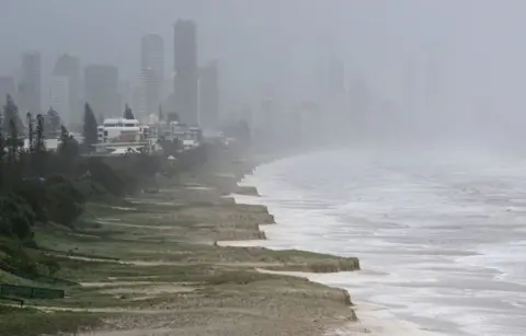 DAVE HUNT/EPA-EFE/REX/Shutterstock A city skyline with tower blocks partially obscured by heavy cloud and a beach beside a stormy sea 