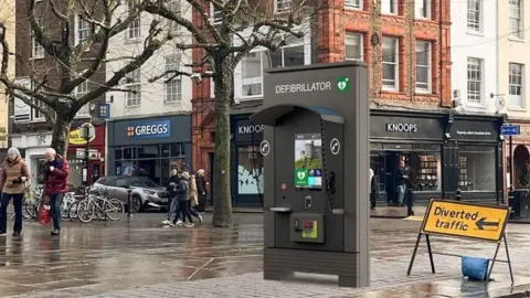 JCDecaux An artist impression of a JCDecaux Communication Hub in St Sampson's Square, York. The hub is about 10 ft in height and the word Defibrillator is visible on the front. There is also a digital screen in the middle.