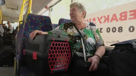 BBC Maria Honcharenko sits on a bus with her cats sitting in a cat carrier on a seat next to her